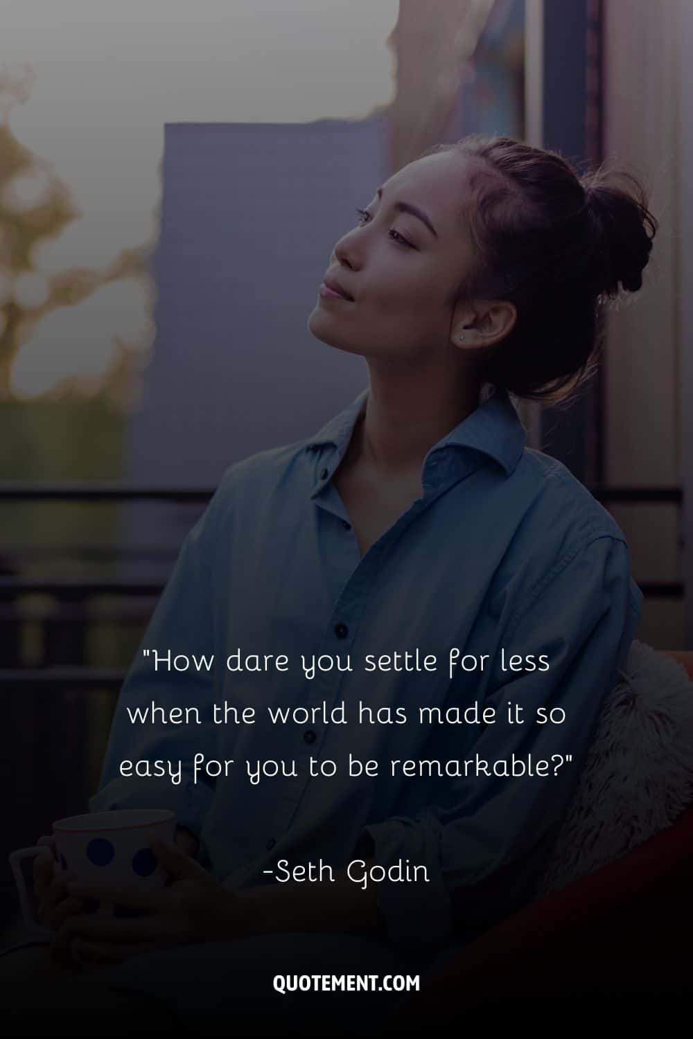 an Asian girl in a blue shirt sitting with a mug in her hands
