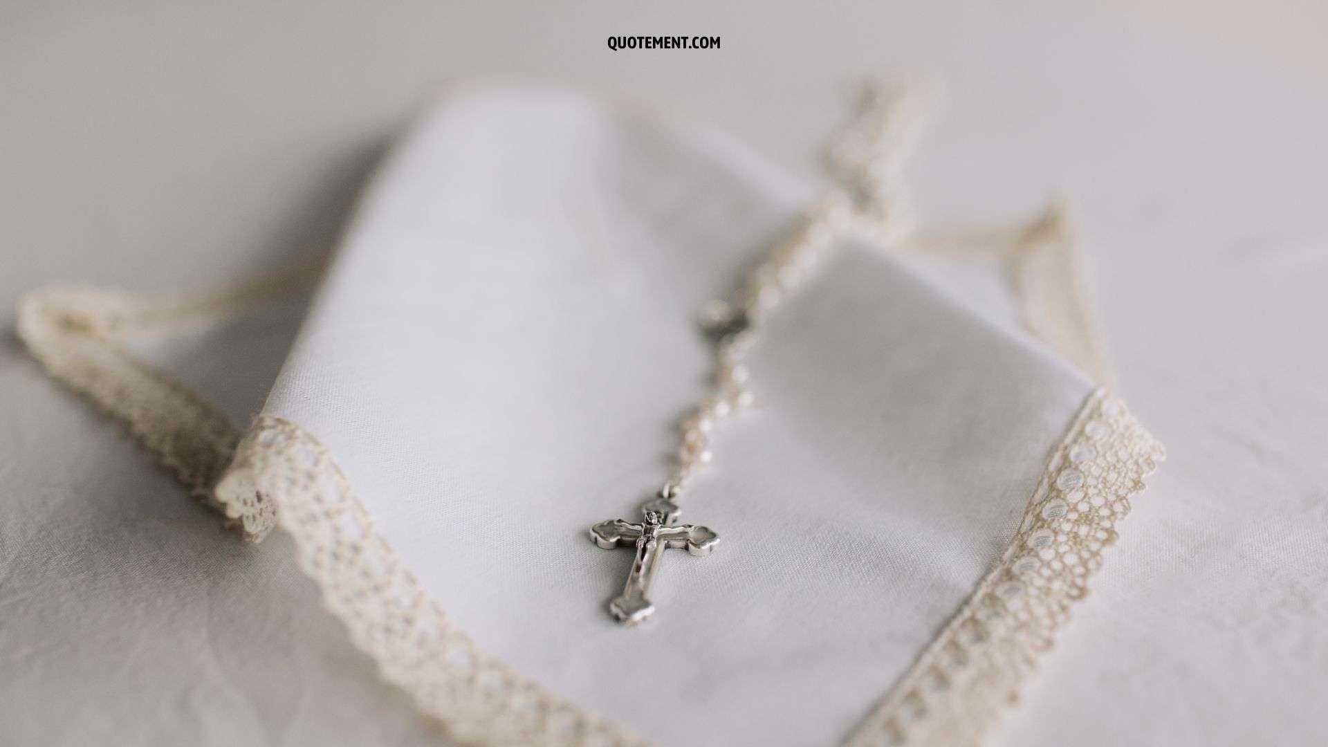 photo of a rosary on a white cloth