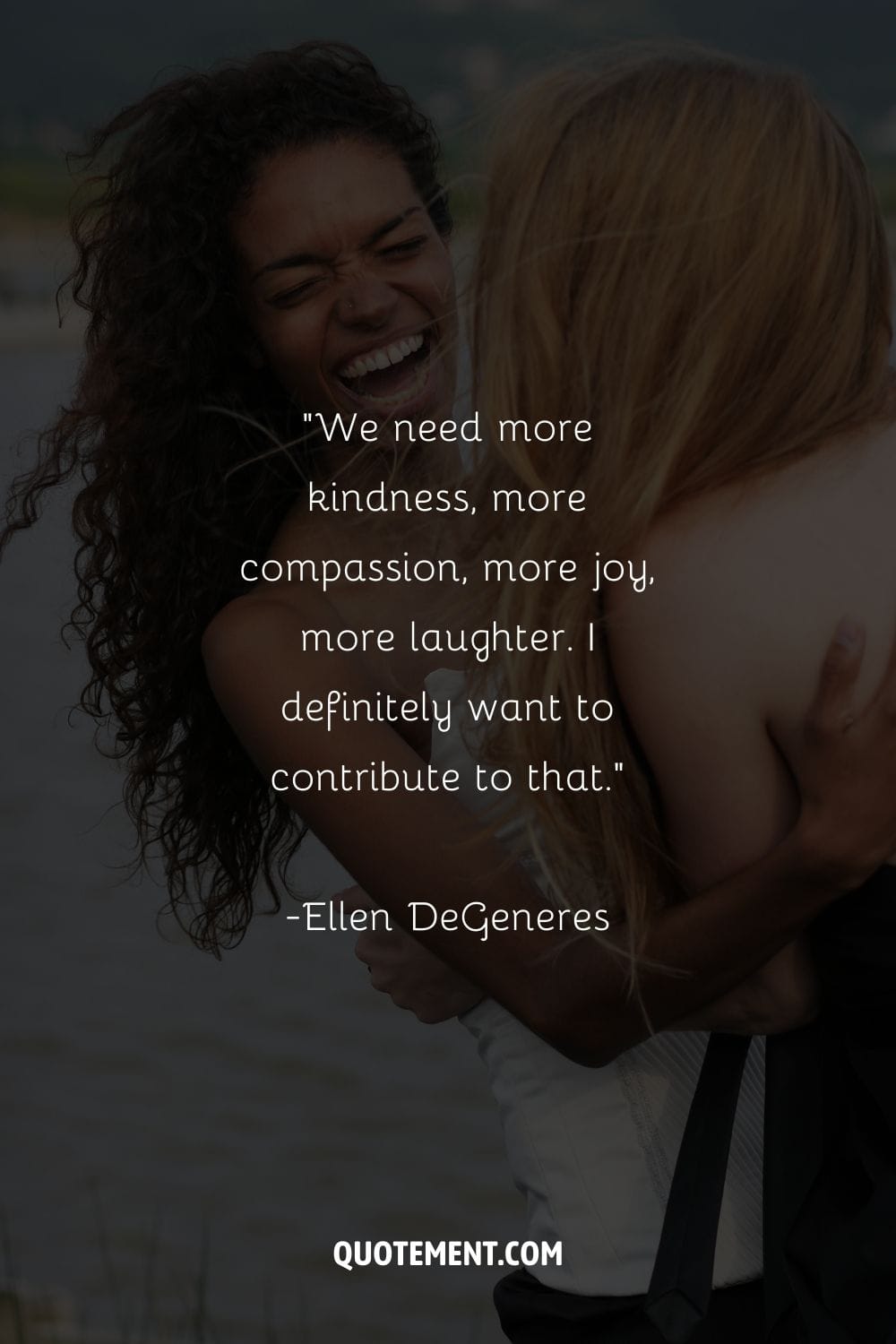 two young women share a hug and laughter with the ocean nearby