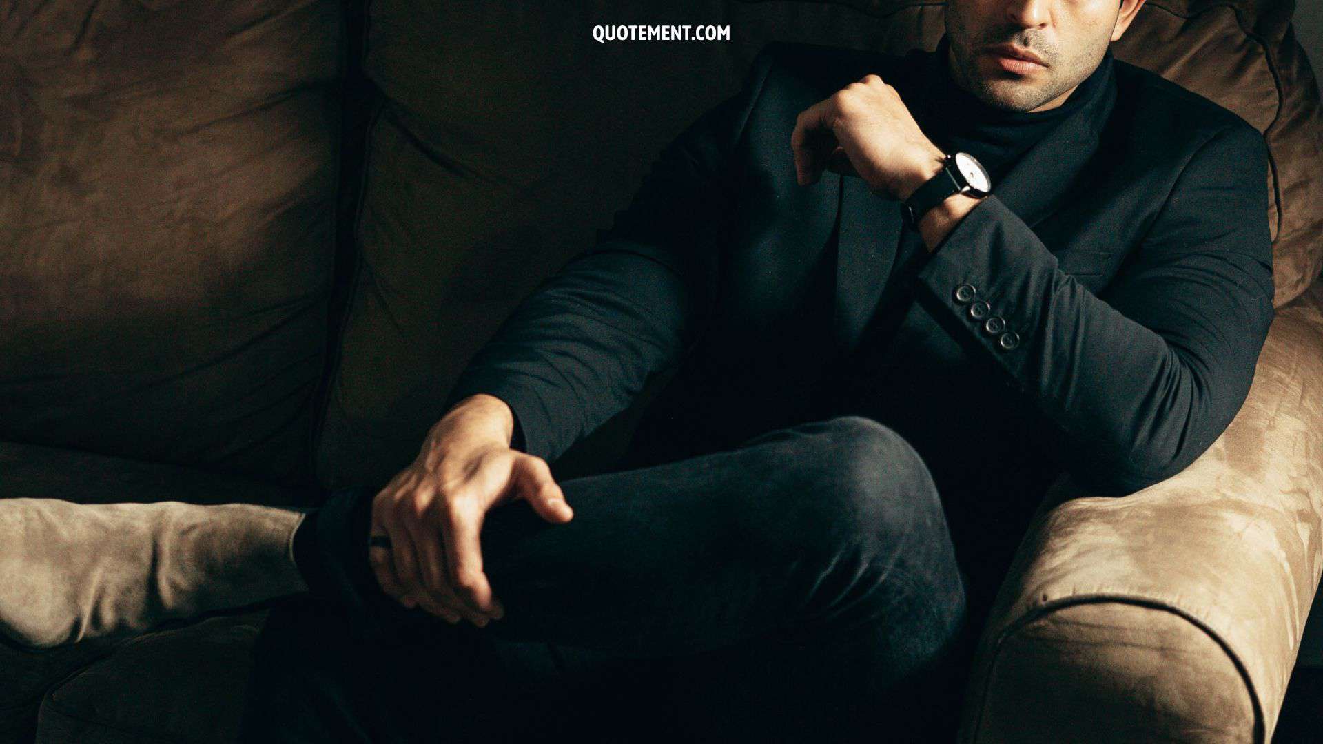 man sitting on a couch in a black suit