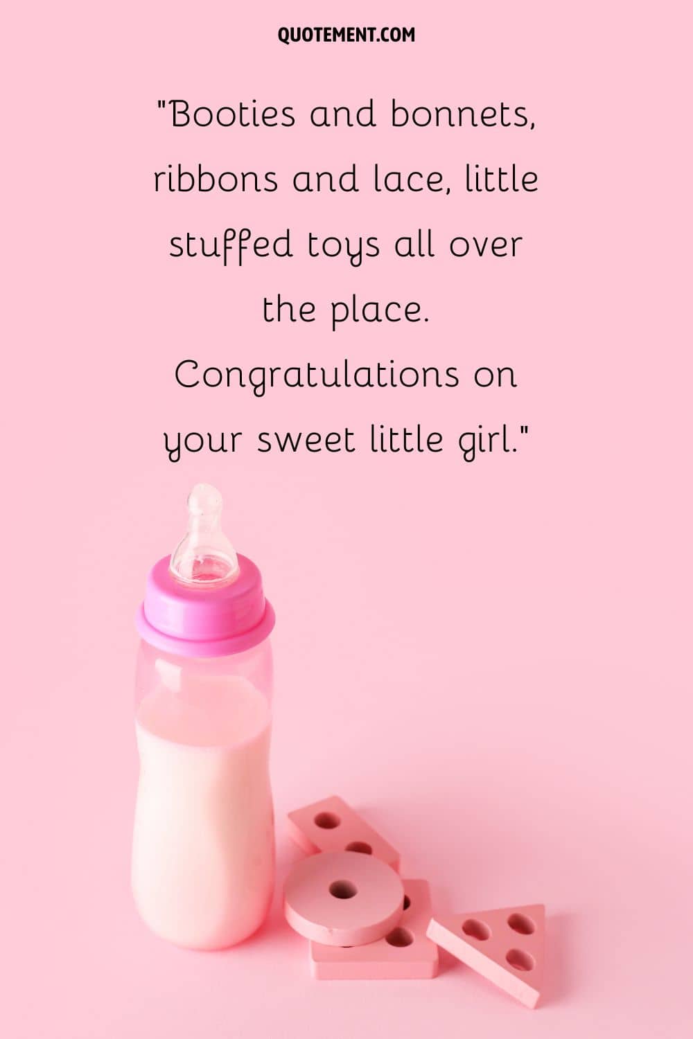 baby bottle and wooden toys on a pink backdrop