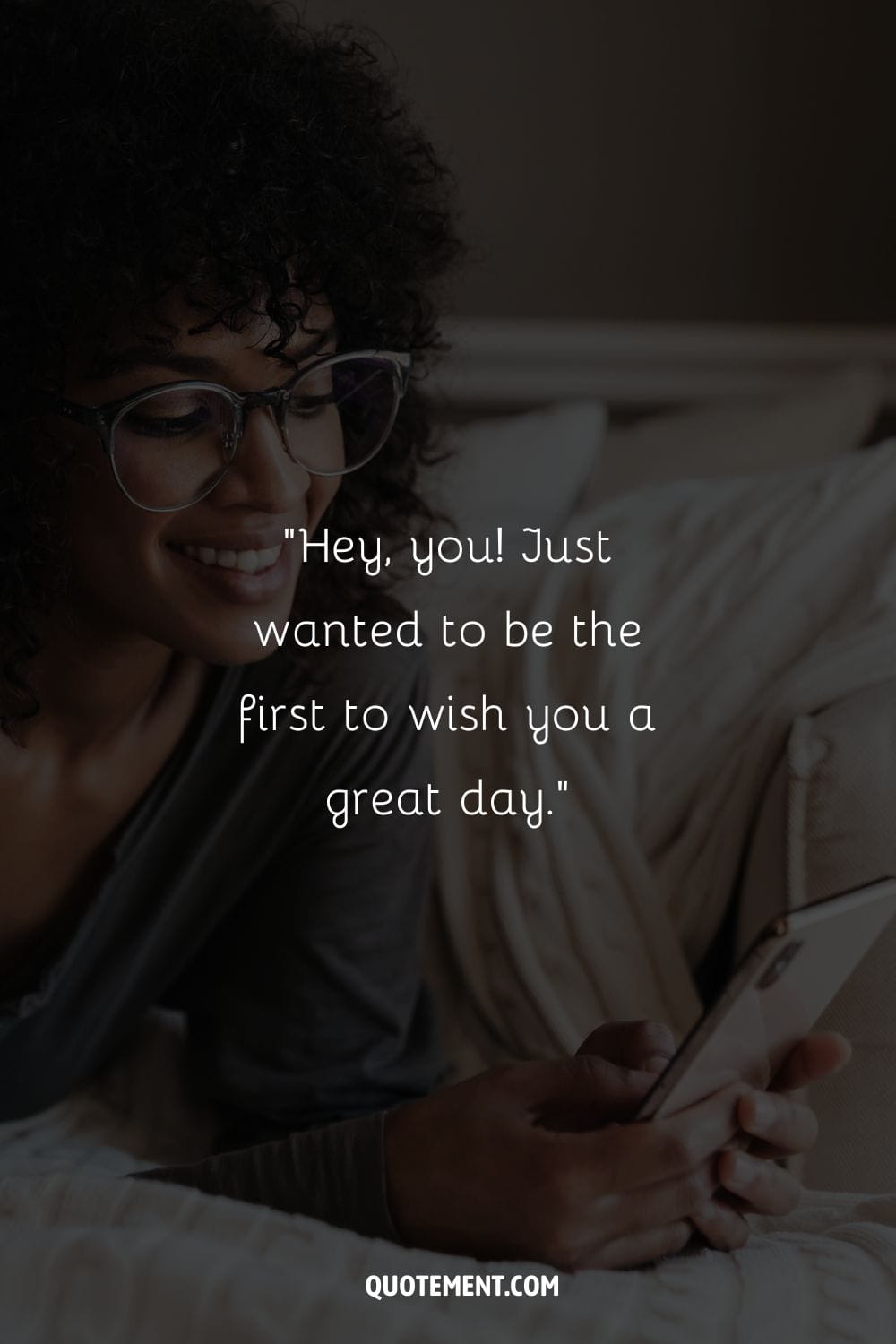 black girl lying in bed, smiling at her phone