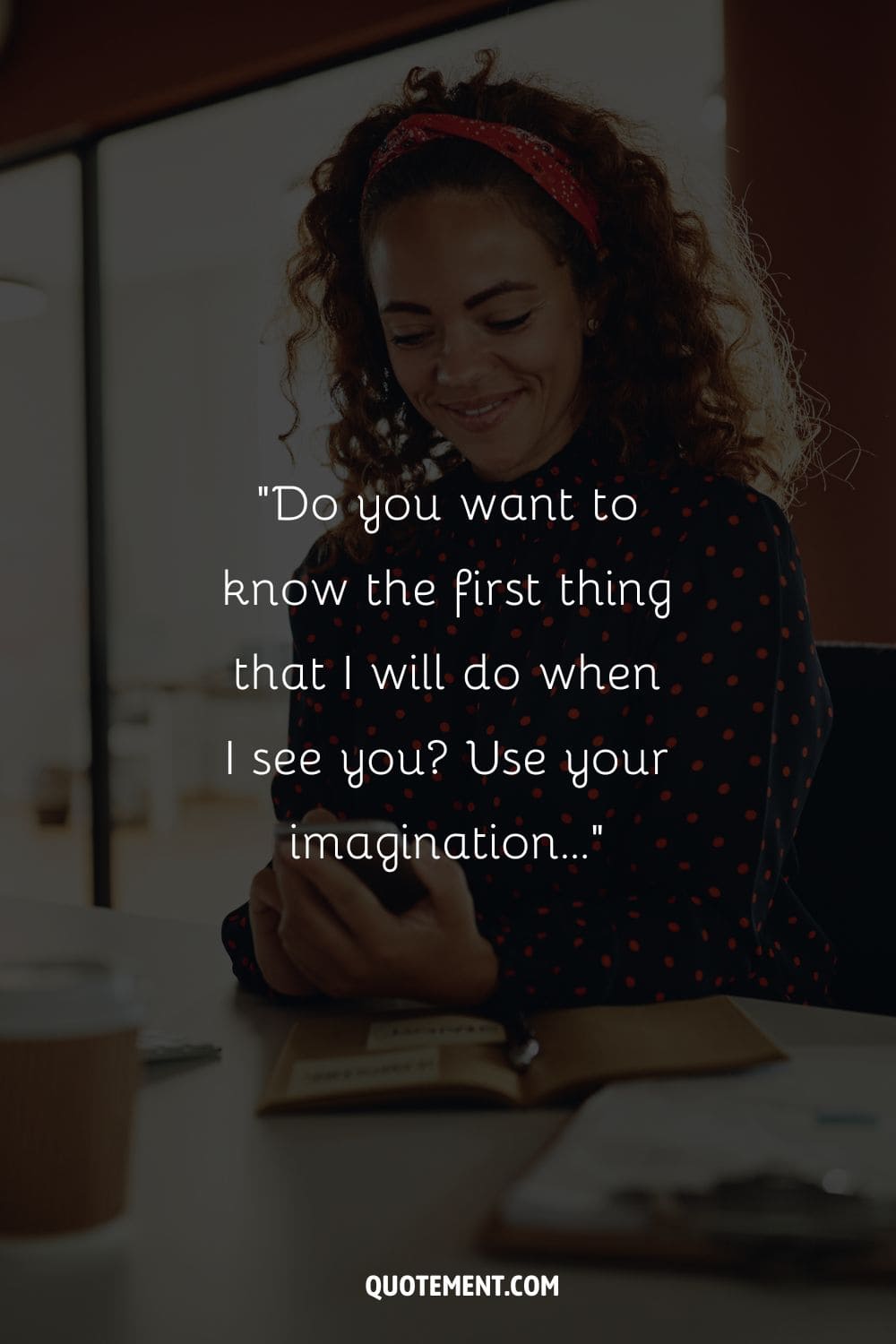 joyful black girl seated at her desk, holding a phone, and smiling