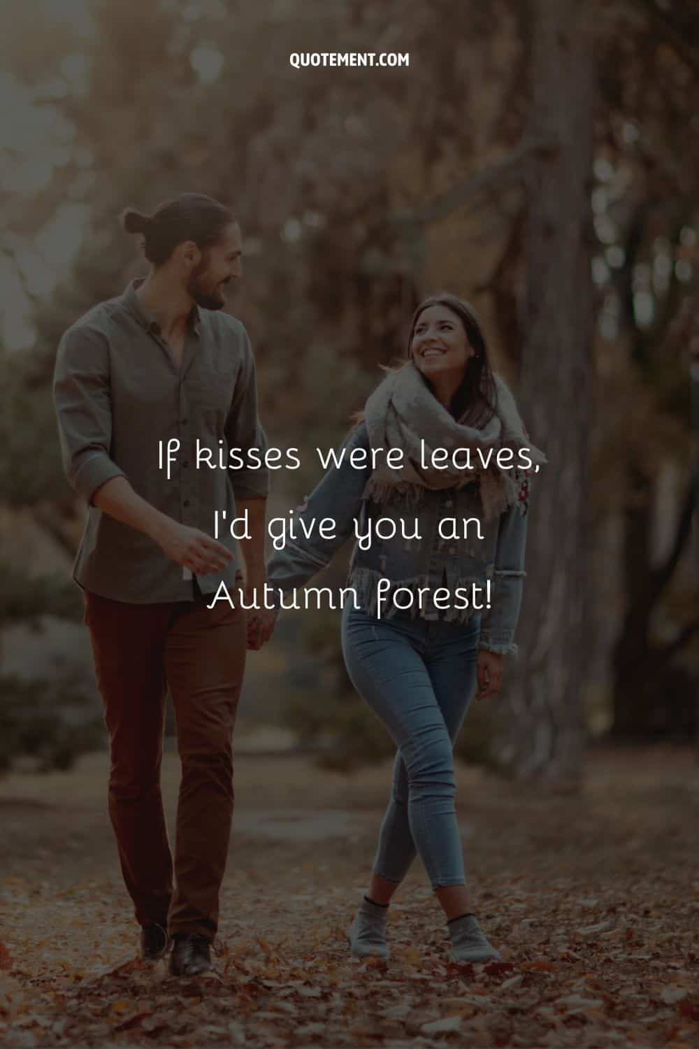 smiling couple walking through fallen leaves, hand in hand