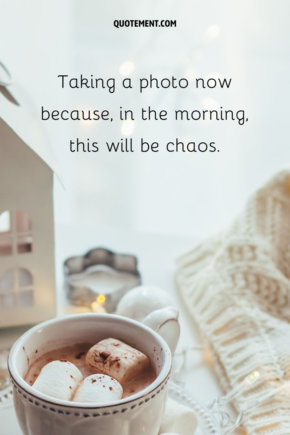 A cup of hot chocolate with marshmallows and warm knitwear in the background