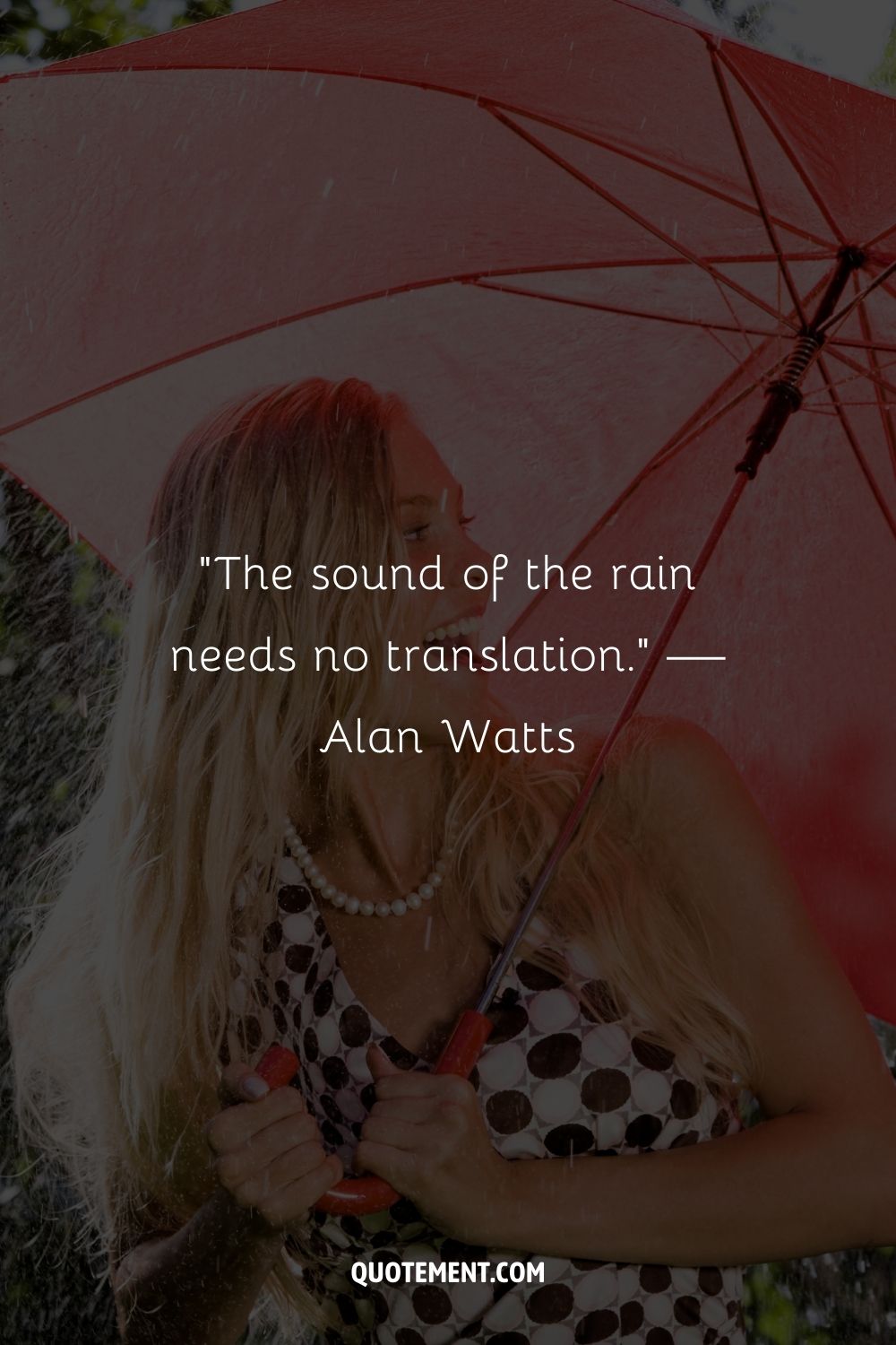 A smiling woman holding tightly to a red umbrella in the rain
