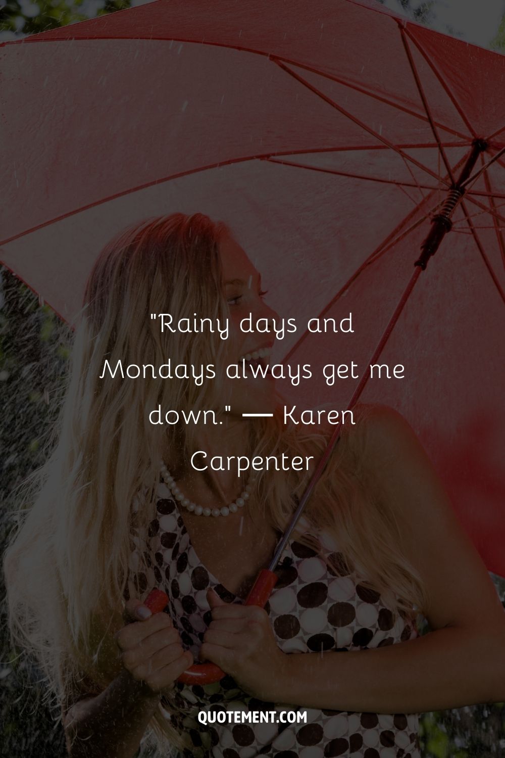 A young woman with long blonde hair standing under a red umbrella amidst falling rain

