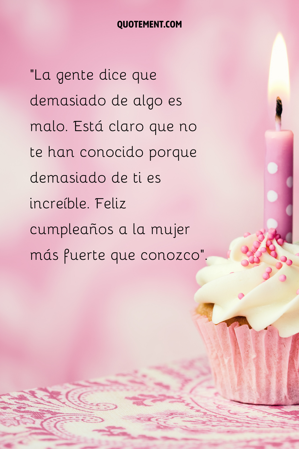 Una sola vela encendida sobre un cupcake rosa con glaseado blanco y virutas rosas