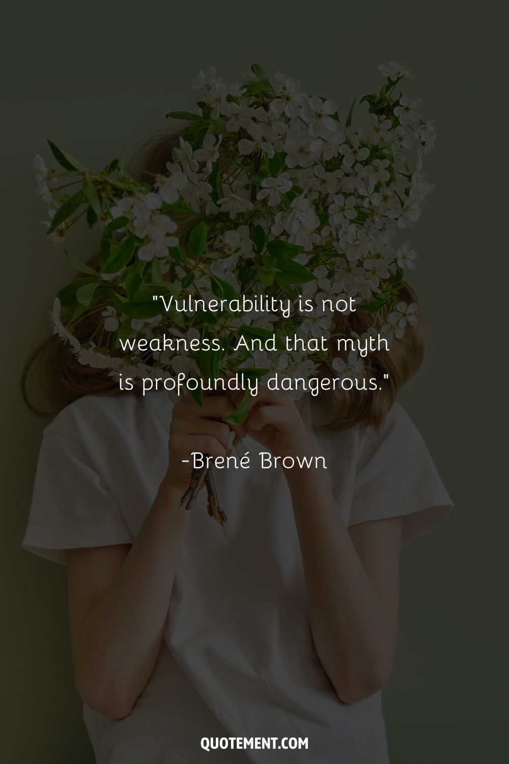 A woman obscured by white blossoms held in front of her face representing a quote about vulnerability
