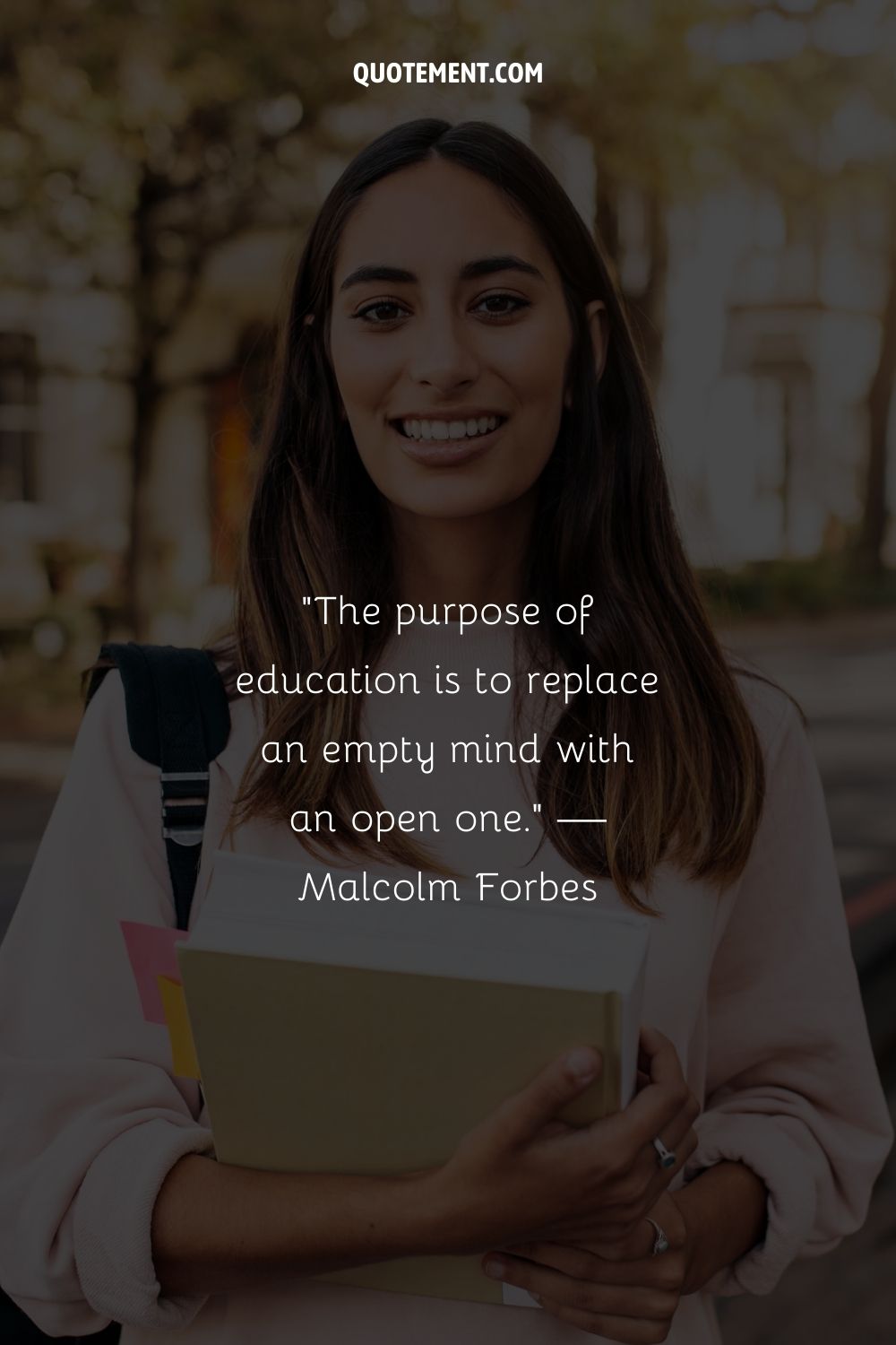 A young smiling woman holding a book representing a quote of motivation for students in high school
