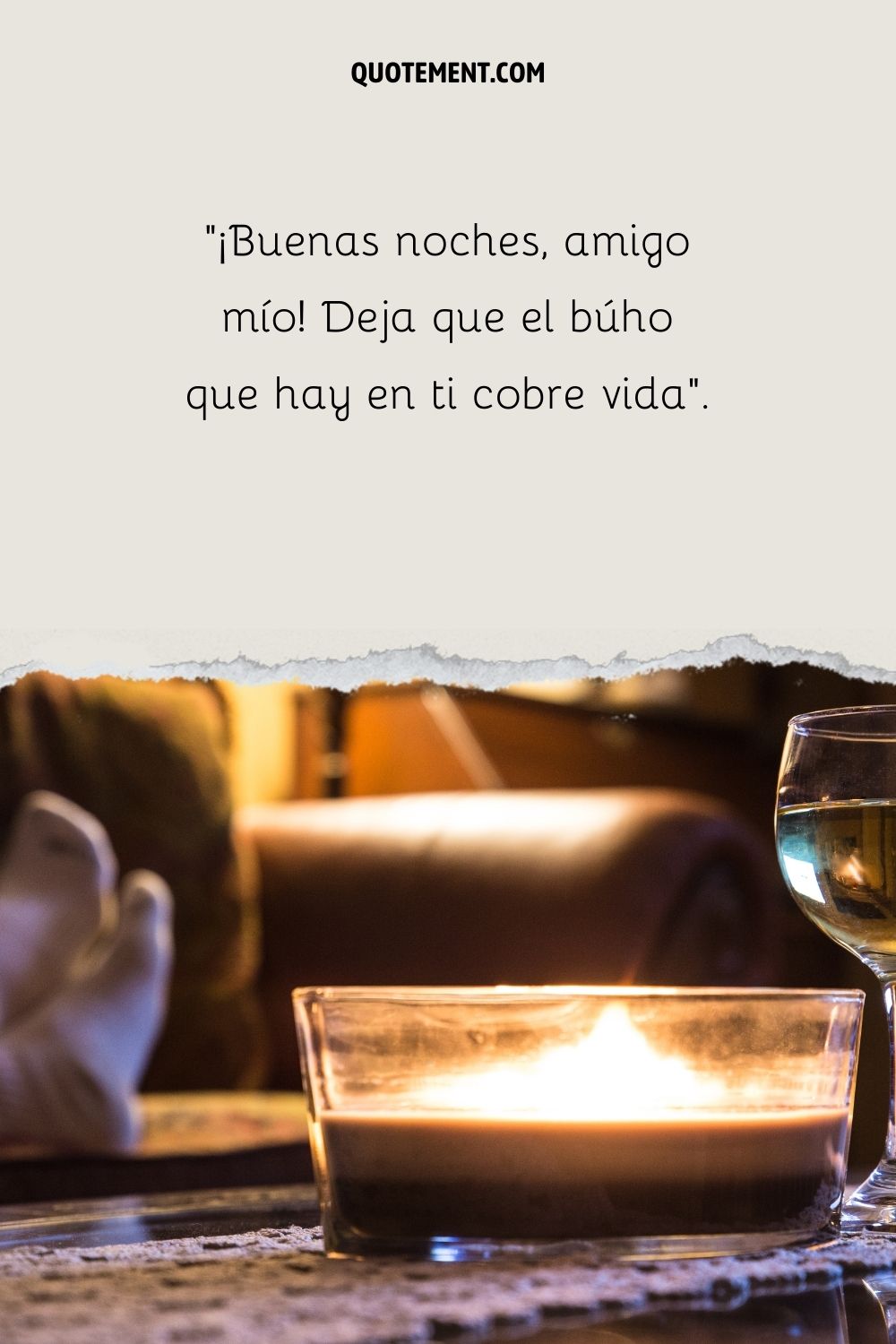 Una vela y una copa de vino sobre una mesa, con una persona al fondo difuminada